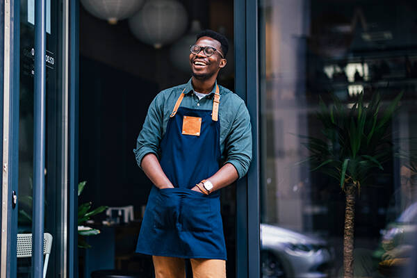 Man wearing apron out front of shop